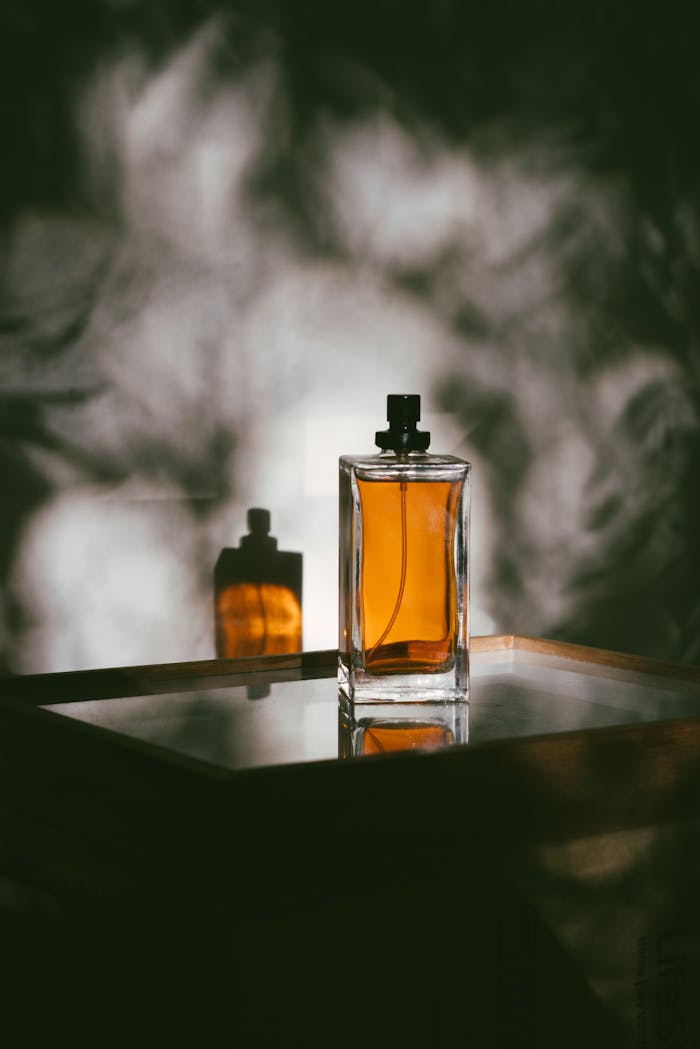 A stylish perfume bottle casting shadows on a&nbsp;reflective surface, creating a&nbsp;moody ambiance.